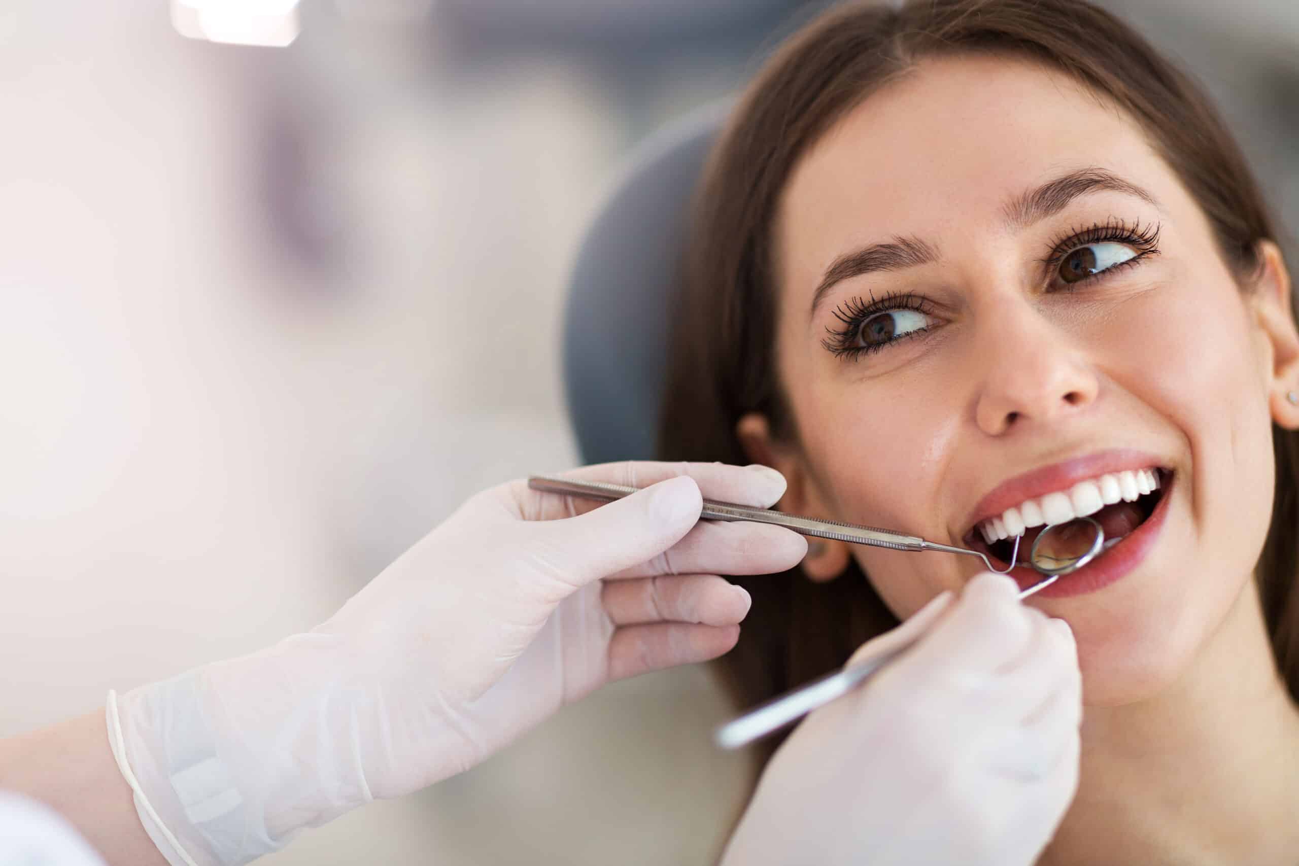 Dentist examining patient’s teeth with mirror
